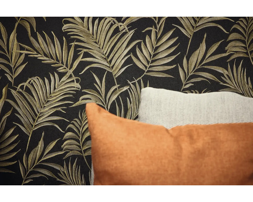 Detail stěny s tapetou s motivem listů a dekorativními polštáři