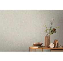 Detail světlé stěny s jemnou vzorovanou tapetou vytvářející klidnou a jednotnou texturu.