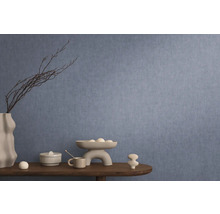 Dekorativní interiér s modrou tapetou, stůl s dekoracemi jako váza, mísa a keramické figurky