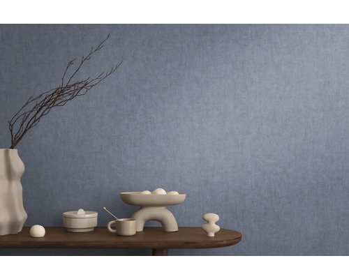 Dekorativní interiér s modrou tapetou, stůl s dekoracemi jako váza, mísa a keramické figurky