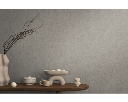 Dekorativní zátiší s vázou, mísou a okrasnými předměty na dřevěném stole před šedou zdí.