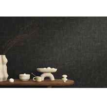 Stylový design pokoje s tmavou vliesovou tapetou a dekorativními prvky na dřevěném stole.