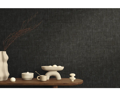 Stylový design pokoje s tmavou vliesovou tapetou a dekorativními prvky na dřevěném stole.