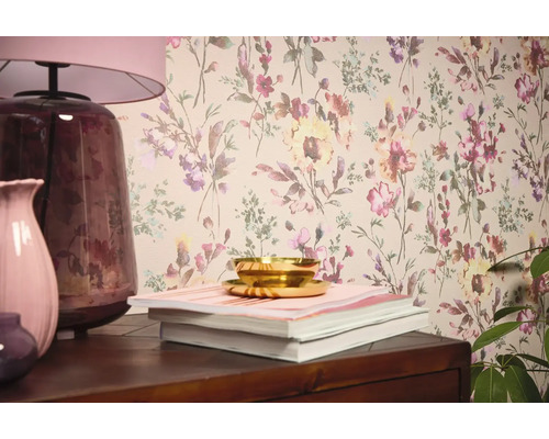 Interiérová scéna s květinovou tapetou, stolní lampou, vázami, knihami a miskou.