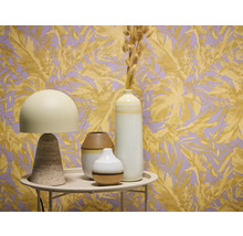 Dekorativní zátiší se stolní lampou a vázami před tapetou s rostlinnými motivy.