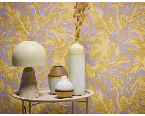 Dekorativní zátiší se stolní lampou a vázami před tapetou s rostlinnými motivy.