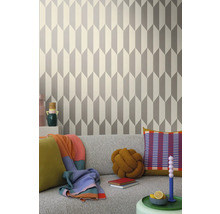 Obývací pokoj s geometrickou tapetou v šedé a bílé barvě za šedou pohovkou