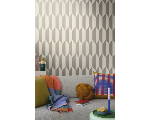 Obývací pokoj s geometrickou tapetou v šedé a bílé barvě za šedou pohovkou