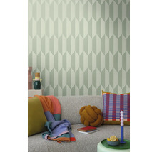 Obývací pokoj s šedou pohovkou, polštáři, přikrývkami a stěnou s geometrickou tapetou