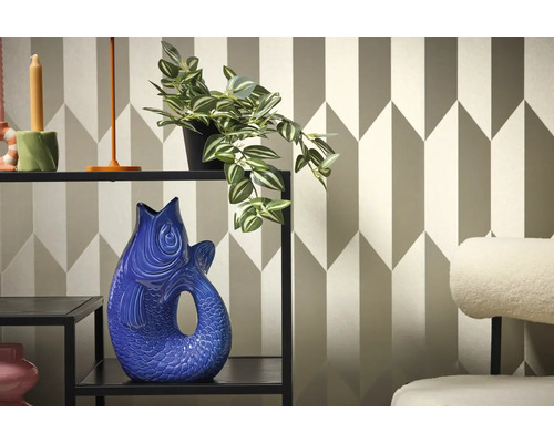 Dekorativní interiér s policí, rostlinou a vázou ve tvaru ryby na pozadí geometrické tapety.