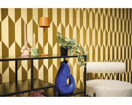 Dekorativní pokoj s regálem, lampou, svíčkami, rostlinou, vázou a židlí před vzorovanou tapetou