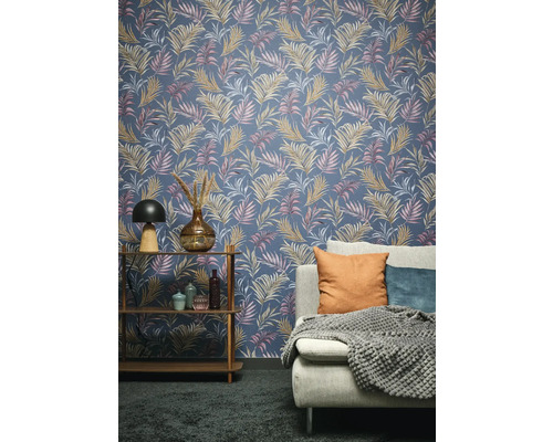 Obývací pokoj s tapetou se vzorem palmových listů, regálem a pohovkou.