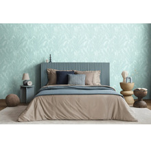 Ložnice s postelí, nočními stolky a tapetou s motivem listů pro relaxační atmosféru.