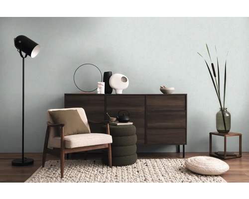 Obývací pokoj s komodou, křeslem, stojací lampou a dekorativními prvky pro útulnou atmosféru