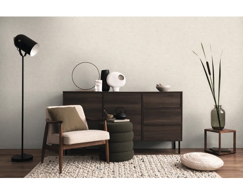 Interiér s křeslem, stojací lampou, komodou a dekorativními prvky pro útulnou atmosféru bydlení.