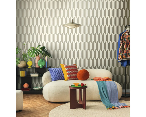 Obývací pokoj s geometrickou tapetou, pohovkou, odkládacím stolkem a dekorativními prvky pro stylové prostředí.