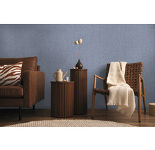 Obývací pokoj s pohovkou, křeslem a odkládacími stolky před modrou stěnou