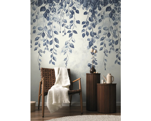 Dekorativní stěna se vzorem listů, křeslo s dekou a příruční stolky v obývacím pokoji.