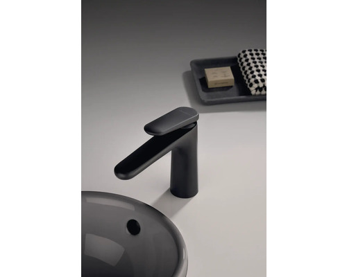 Černá umyvadlová baterie vedle umyvadla, mýdla a ručníku