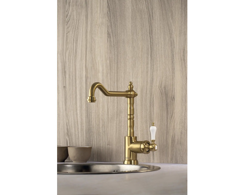 Zlatá kuchyňská baterie s bílou rukojetí namontovaná v umyvadle