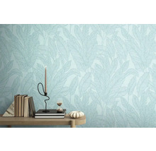 Detail stěny s tapetou se vzorem listů, zdobené knihami, svíčkou a přesýpacími hodinami