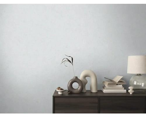 Dekorativní komoda s vázami, knihami a lampou před světlou stěnou