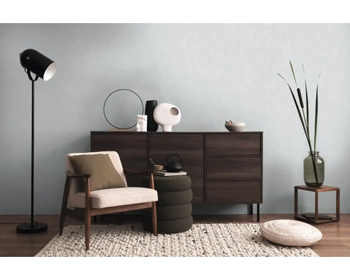 Obývací pokoj s komodou, křeslem, stojací lampou a dekorativními prvky pro útulnou atmosféru