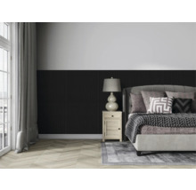 Ložnice s postelí, nočním stolkem a lampou před stěnou s dřevěným obložením