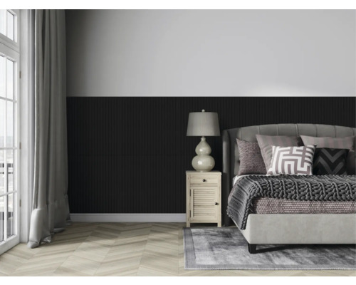 Ložnice s postelí, nočním stolkem a lampou před stěnou s dřevěným obložením