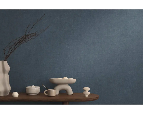 Modrá vliesová tapeta v obývacím pokoji s dekorací na dřevěném stole.