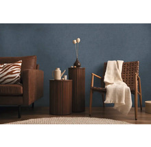 Obývací pokoj s pohovkou, křeslem, odkládacími stolky a dekorací před modrou stěnou