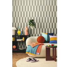 Obývací pokoj s geometrickou tapetou, pohovkou, odkládacím stolkem a dekorativními doplňky pro stylový interiér.