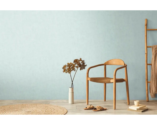 Světlá místnost se židlí, vázou, dekorací a kulatým kobercem pro útulnou atmosféru.