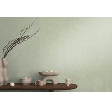 Dekorativní scéna s vázou, větvemi a různými předměty na stole před stěnou