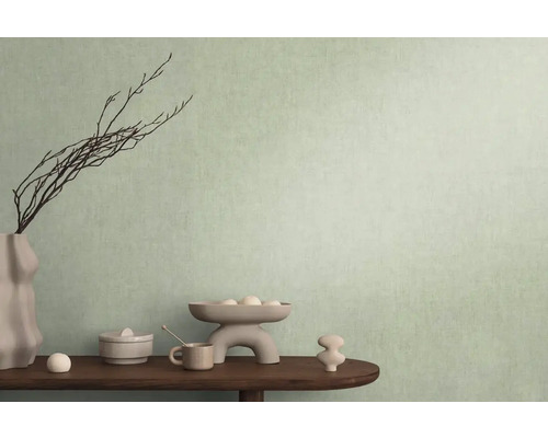 Dekorativní scéna s vázou, větvemi a různými předměty na stole před stěnou