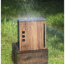 Dřevěná zahradní sprcha na dřevěném podstavci, zavlažovaná na trávníku