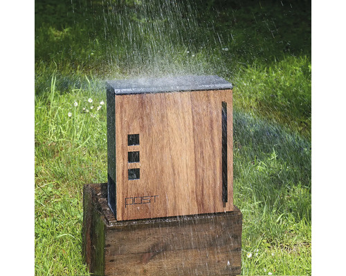 Dřevěná zahradní sprcha na dřevěném podstavci, zavlažovaná na trávníku