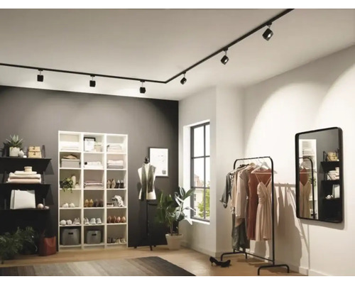 Moderní šatna s černým kolejnicovým systémem a variabilními bodovými světly pro flexibilní osvětlení.
