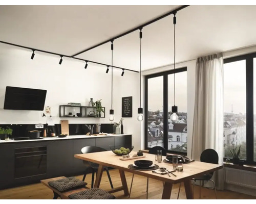 Moderní kuchyně s lineárním kolejnicovým systémem a závěsnými světly nad dřevěným stolem.