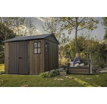 Zahradní scéna s dřevěným zahradním domkem a osobou sedící na zahradní lavičce