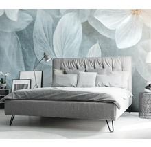 Ložnice s postelí, nočním stolkem a dekorativním květinovým motivem na zdi.