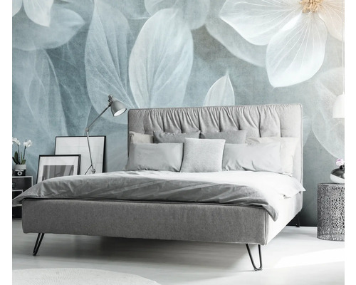 Ložnice s postelí, nočním stolkem a dekorativním květinovým motivem na zdi.