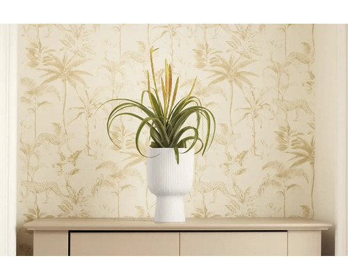 Dekorativní umělá rostlina v bílém květináči na komodě