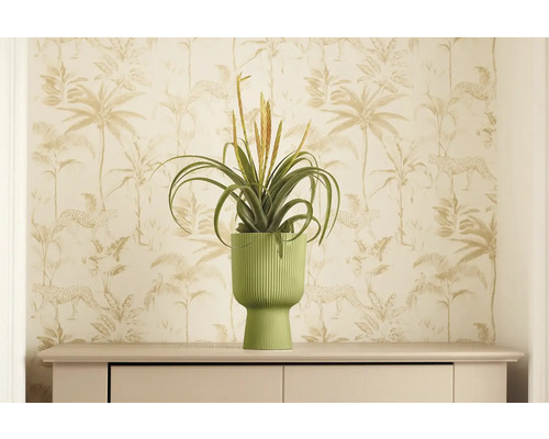 Dekorativní umělá rostlina v žebrovaném květináči na komodě před vzorovanou tapetou