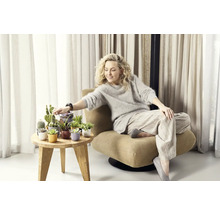 Žena sedí v křesle vedle odkládacího stolku s různými kaktusy a sukulenty v ozdobných květináčích.