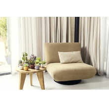 Křeslo s polštářem vedle stolu s hrnkovými rostlinami před závěsy