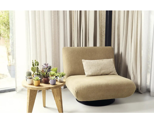 Křeslo s polštářem vedle stolu s hrnkovými rostlinami před závěsy