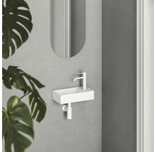 Malé bílé umyvadlo s baterií a zrcadlem v koupelně