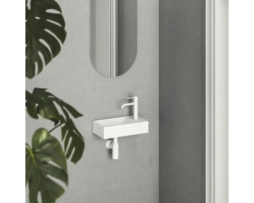 Malé bílé umyvadlo s baterií a zrcadlem v koupelně