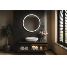 Koupelna s kulatým zrcadlem s osvětlením, umyvadlem a rostlinou